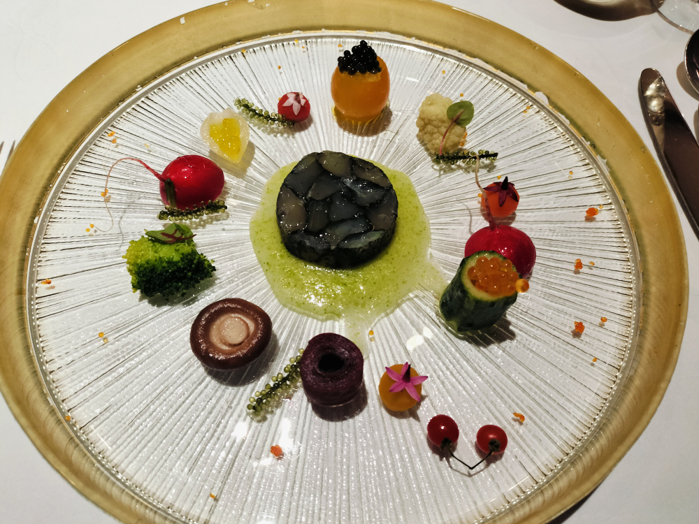 円状にさまざまな前菜が盛られている丸いガラスのデザイン皿