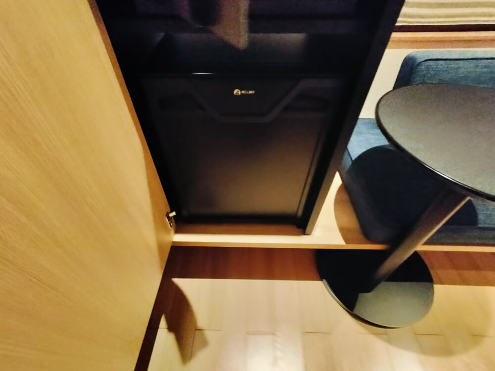 お部屋備え付けの冷蔵庫、中身はなし。冷蔵庫の上に金庫がある。