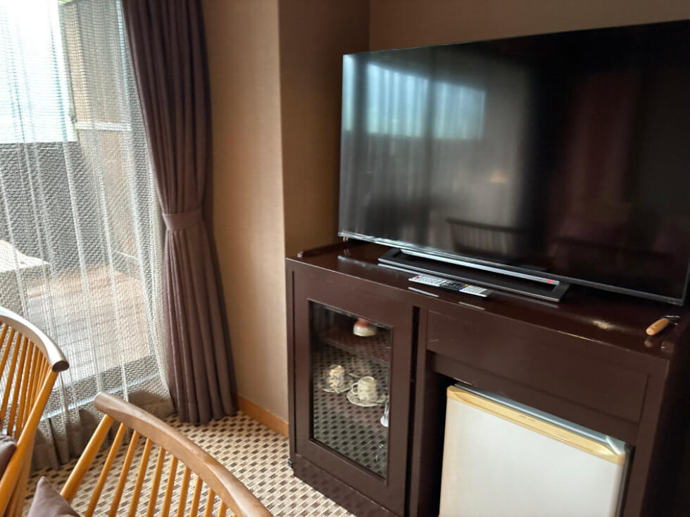 窓際のキャビネット。上にはテレビ。下には冷蔵庫やカップ類など